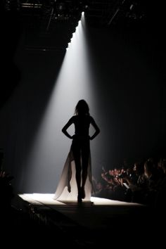 a woman walking down a runway in front of a crowd