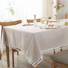 a dining room table covered with a white and beige striped tablecloth