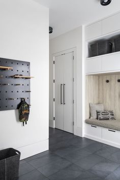 a room with white walls and black tile flooring that has hooks on the wall