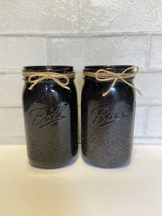 two black mason jars with twine string tied around the lids on a white counter