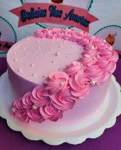 a pink cake decorated with flowers and pearls on a purple tableclothed table cloth