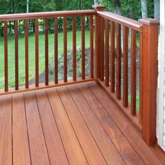 a wooden deck with railing and trees in the background