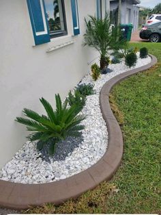 a house with some plants and rocks in the front yard, next to it is a car