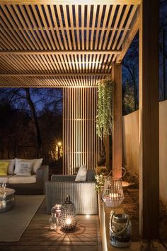 an outdoor living area with wicker furniture and lanterns lit up at night, surrounded by wood slats