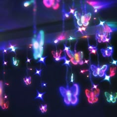 some lights that are hanging in the air with butterflies on one side and stars on the other