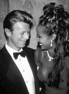 a man in a tuxedo and a woman in a dress smile at each other