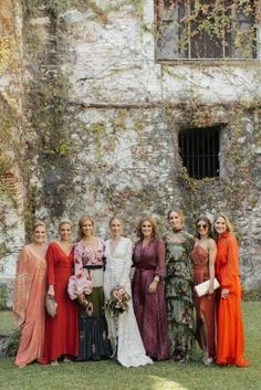 a group of women standing next to each other in front of a stone building with ivy growing on it