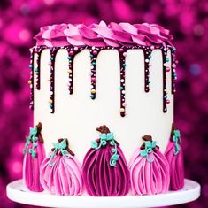 a white cake with pink frosting and purple decorations