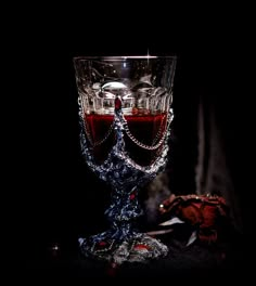 a crystal goblet with red liquid in it on a black tableclothed surface