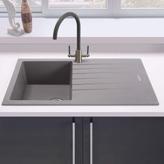 a kitchen sink with a faucet in the middle and a window behind it