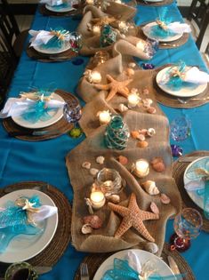 the table is set with blue and white plates, silverware, and starfish napkins