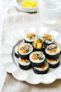 sushi on a white plate next to a glass of water