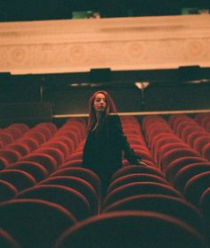 a woman with red hair standing in an empty auditorium