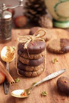 a stack of cookies sitting on top of a wooden cutting board next to spoons