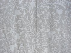 an embroidered fabric with white flowers and leaves on it, as seen from the side