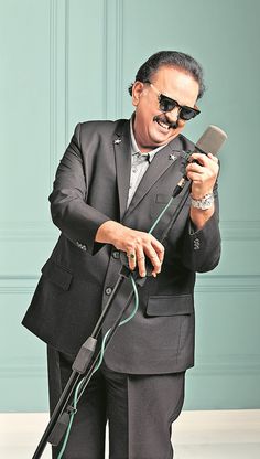 a man in a suit and sunglasses holding a microphone