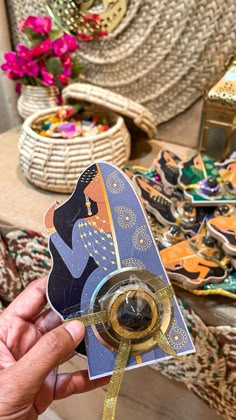 a hand holding a piece of paper with an egyptian design on it and some other items in the background