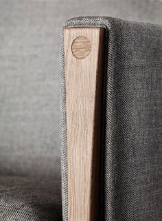 a close up view of a wooden object on a gray fabric couch with wood buttons