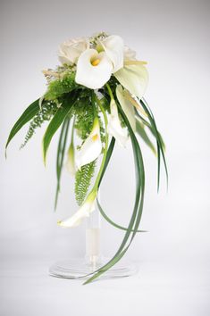 a vase filled with white flowers and greenery