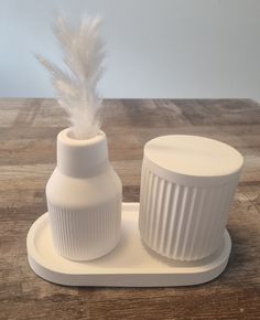 a white container with a feather on it sitting on a wooden table next to an empty bottle