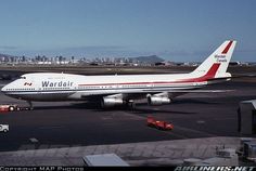 an airplane that is sitting on the tarmac in front of some buildings and cars