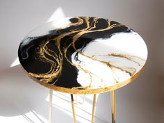 a black and white marble topped table with gold accents on it's legs, against a white wall