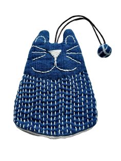 a blue purse with a cat face on it's side and a ball hanging from the front