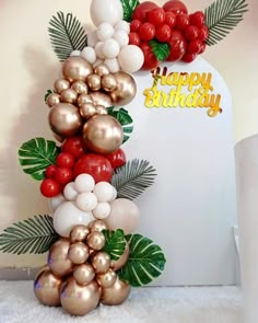 a birthday cake decorated with balloons and palm leaves on the top is red, white and gold