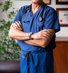 a man in scrubs is standing with his arms crossed