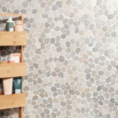 a bathroom with stone wall and shelves holding personal care products on it's sides