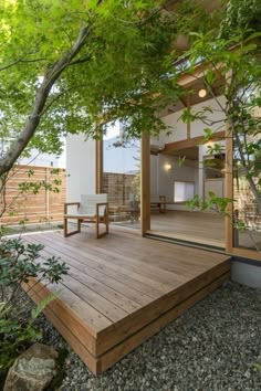 a wooden deck in the middle of a yard with trees and rocks around it, surrounded by greenery