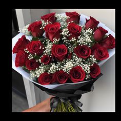 a bouquet of red roses with baby's breath in the center is being held by someone