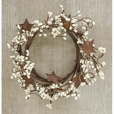 a wreath with white flowers and brown leaves on a wooden surface, hanging from the wall