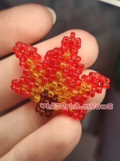 a hand holding a red and yellow beaded ring