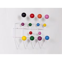 a multicolored wall hanging on the side of a white wall with several balls attached to it