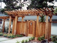 an outdoor wooden structure in front of a house with plants and flowers around it,