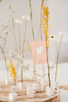 flowers and marshmallows are arranged on a piece of wood with a card