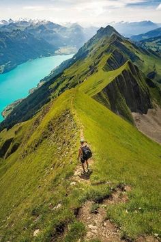 a man hiking up the side of a mountain with a lake in the middle of it