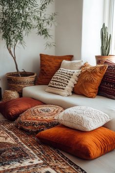 a living room filled with lots of pillows on top of a white couch next to a potted plant