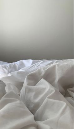 an unmade bed with white sheets and pillows