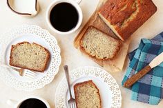 slices of banana bread on plates next to two cups of coffee and napkins with forks