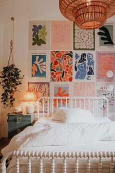 a white bed sitting in a bedroom next to a wall with pictures on the walls