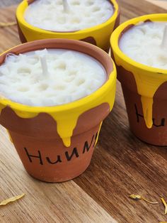 three clay pots filled with liquid sitting on top of a wooden table