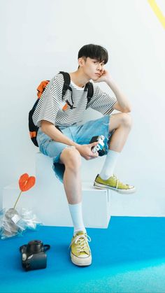 a young man sitting on top of a white bench next to a pair of shoes