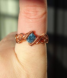 a woman's hand holding a ring with a blue topazte in it