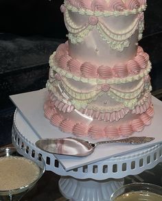 a three tiered cake sitting on top of a table next to two glasses and spoons