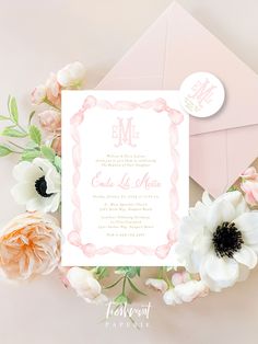 the wedding stationery is surrounded by flowers and pink envelopes on top of an envelope