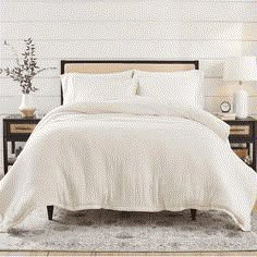 a bed with white sheets and pillows in a room