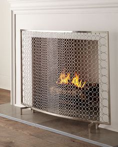 a fireplace with a fire in the middle and a metal screen on it's side