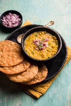 a black plate topped with crackers and a bowl filled with corn next to it